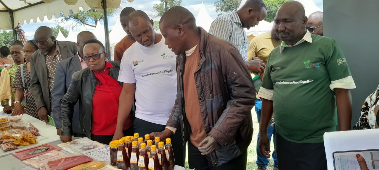 UDPL members and partners inspecting bottled honey at a market stall